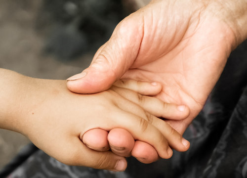 Hands of a little girl and an old grandmother. Hands of a little kids holding elderly man, World Kindness Day concept