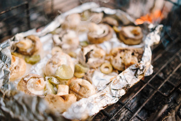 Brown champignon portobello mushrooms being cooked on char grill