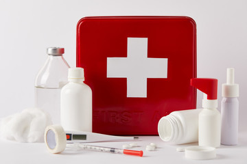 close-up shot of red first aid kit box with various medical bottles and supplies on white