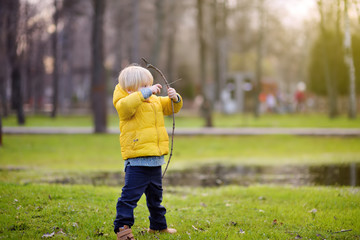 Little boy playing with sticks during stroll in the park