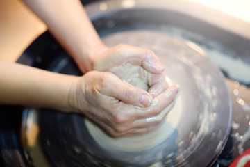 Close-up photo of hands of woman making clay object
