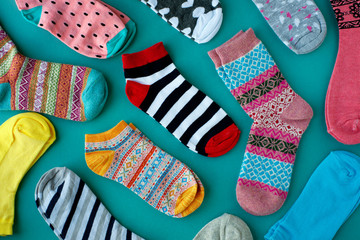 Many socks are scattered on a turquoise background. Knitted socks for cold seasons. View from above.