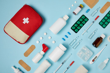top view of first aid kit bag with composed medicines on blue surface