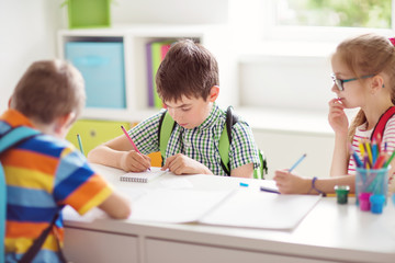 Fototapeta premium Children sitting in the room with books. Pupils writing at school