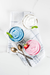 Healthy diet summer dessert, vanilla and berry frozen yogurt or  soft ice cream in white bowls, white marble background copy space top view