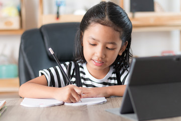 Asian little girl doing homework and pointing finger on wooden table select focus shallow depth of field