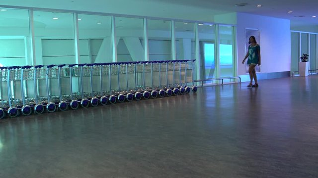 The woman at the airport takes a trolley for luggage and puts it in the bag