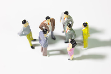 A group of miniature businessman  stand meeting on white background top view closeup.