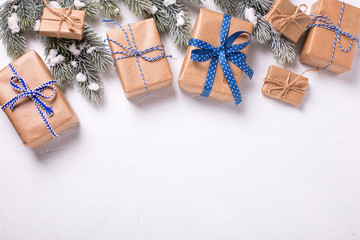 Border from wrapped christmas presents and fur tree branches on  white textured  background.