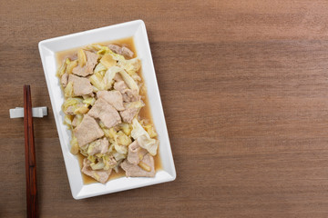 top view of stir fried pork with cabbage and oyster sauce in a plate on wooden table. asian hommade style food concept.