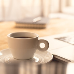Coffee cup and laptop at office desk. Morning coffee at work.