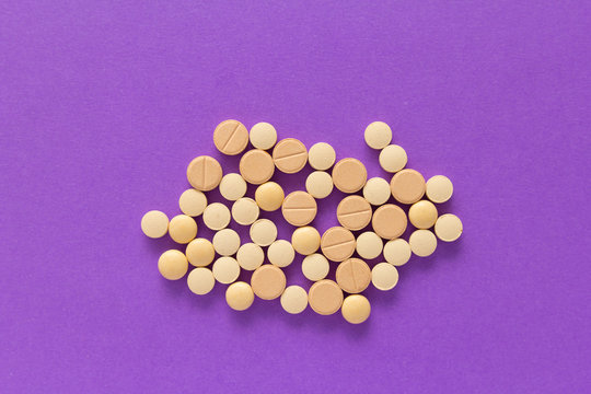 Group of assorted beige tablets. Violet background.