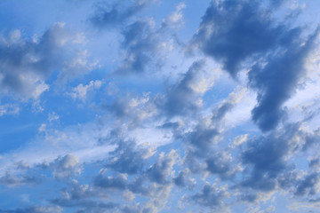 Evening blue sky with clouds at sunset. Clouds are illuminated by the rays of the setting sun.
