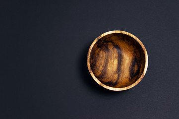 Wooden utensils for the kitchen, bowls, plates on a black background. The concept of natural dishes, a healthy lifestyle. Texture of wood.