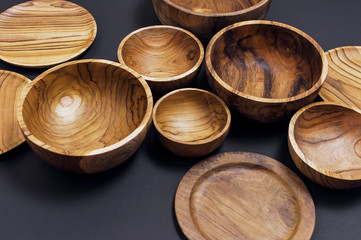 Wooden utensils for the kitchen, bowls, plates on a black background. The concept of natural dishes, a healthy lifestyle. Texture of wood.