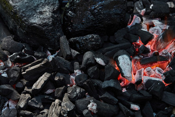 Orange wild fire burning on black coal and ash, prepared for barbecue grill