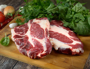 fresh raw meat, herbs and spices on a cutting board on a wooden background
