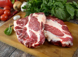 fresh raw meat, herbs and spices on a cutting board on a wooden background