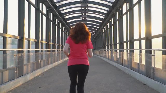 red-haired athletic woman passionate about Jogging in urban environment,slow motion