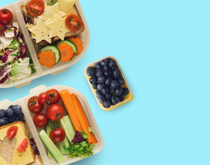 Lunch boxes with healthy food, isolated on blue