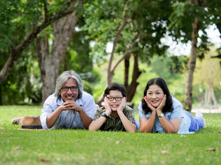 Fototapeta premium Grandparents spend the time with grandson,They are laying on grass in the garden at home.