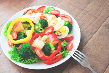 Boiled egg and vegetables salad on white dish on wooden table