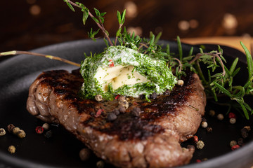 English cuisine. a large piece of a juicy steak of beef, veal, mutton or pork, lies on a cast-iron frying pan, with cream cheese and herbs, thyme, marasm.