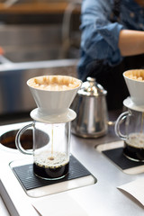 The proccess of hand dripping coffee in the coffee shop. Barista on the background.