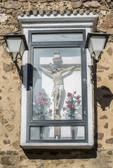 Christian crucifix stands encased and attached outdoors to wall of Church, Saceruela, Spain