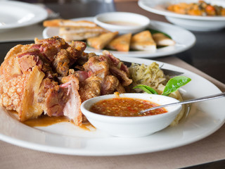 Crispy fried pork leg placed on a plate with vegetables and seasoning sauce