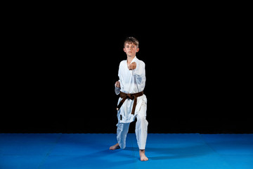 Young boy training karate on black background