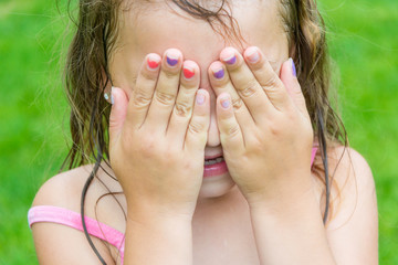 Child girl don't see, covering her eyes and face by hands