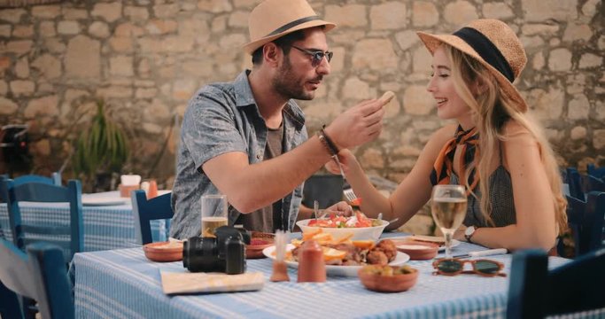 Young tourists couple eating lunch at traditional Greek tavern