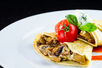 Homemade tasty pancakes blinis served with mushrooms and tomat