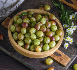 round wooden bowl with green gooseberries