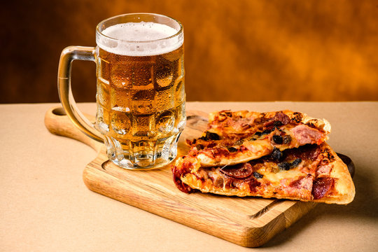 Slice of delicious homemade pizza served with light cold beer on