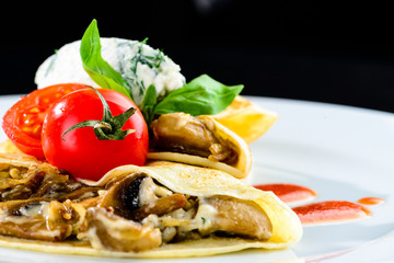Homemade tasty pancakes served with mushrooms and tomat