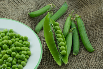 Fresh harvest green pea pods and peas from my garden on brown jute background 