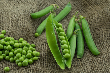 Fresh harvest green pea pods and peas from my garden on brown jute background 