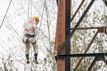 Industrial climber in uniform and helmet working on height outdoors. Professional worker doing his risky job on water tower.