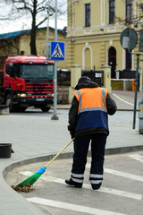 Worker of cleaning company sweeping, cleaning city street with b