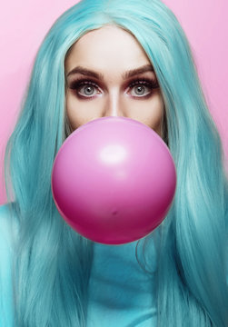 Beautiful young woman face close up, blowing a balloon 