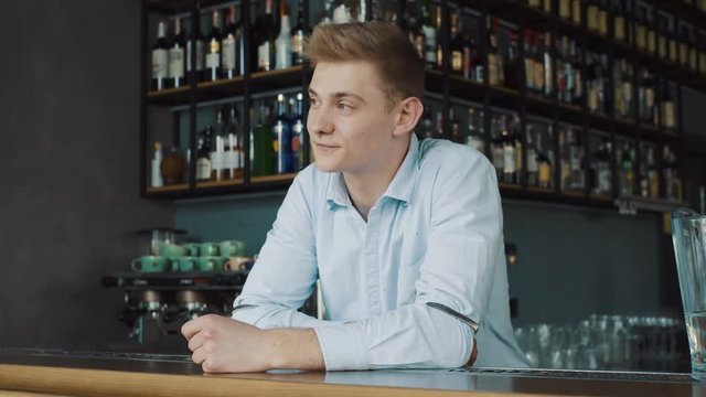 Portrait of a happy young bartender behind the counter