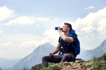 Thirsty male hiker drinking water and enjoying the view