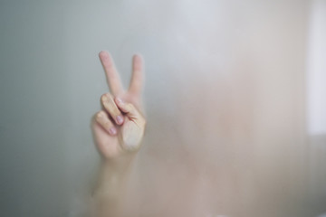 Female hands behind the glass in the bathroom.