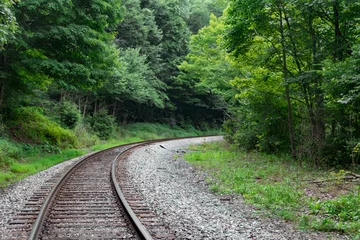 Papier Peint photo Chemin de fer Train tracks lead into a curve or bend in the forest of West Virginia.