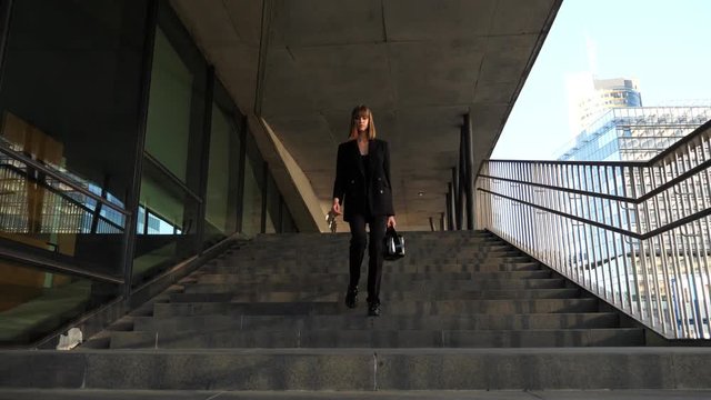 Young woman walking downstairs in slow motion, city, long shot