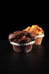 Chocolate muffin and nut muffin, homemade bakery on dark background.