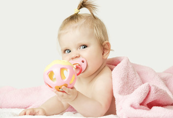 Studio portrait of adorable baby girl playing with plastic rattle toy