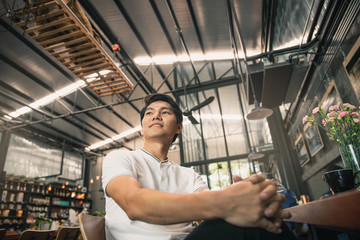 Young man relaxing in cafe,drinking coffee and smiling. Young smiling successful man sitting in cafe.